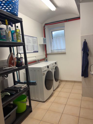 Waschsalon Waschküche mit Waschmaschinen, Regalen und einem Eimer in einem hellen Raum.